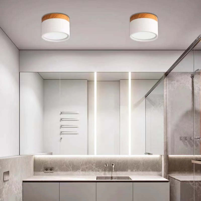 Two white Clérachic Wood-Grain Cylinder Ceiling Lights unlit on a ceiling above a stone vanity and long mirror.