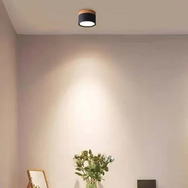 A black Clérachic Wood-Grain Cylinder Ceiling Light casting a soft scallop of light down a warm beige wall.