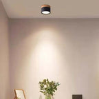 A black Clérachic Wood-Grain Cylinder Ceiling Light casting a soft scallop of light down a warm beige wall.