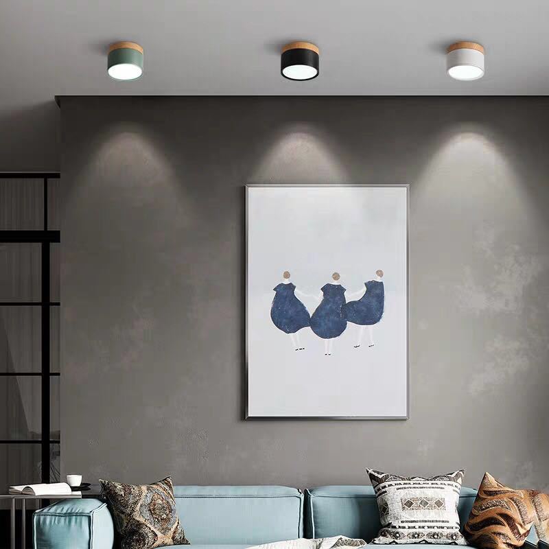Green, black and white Clérachic Wood-Grain Cylinder Ceiling Lights in a row, scalloping a grey living room wall.