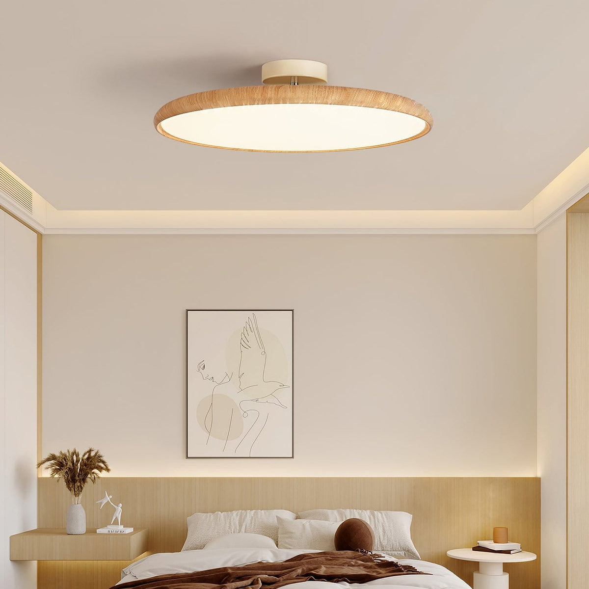 A light wood-grain Clérachic ceiling light lit warm over a bedroom with a pale wood headboard and a framed line drawing.