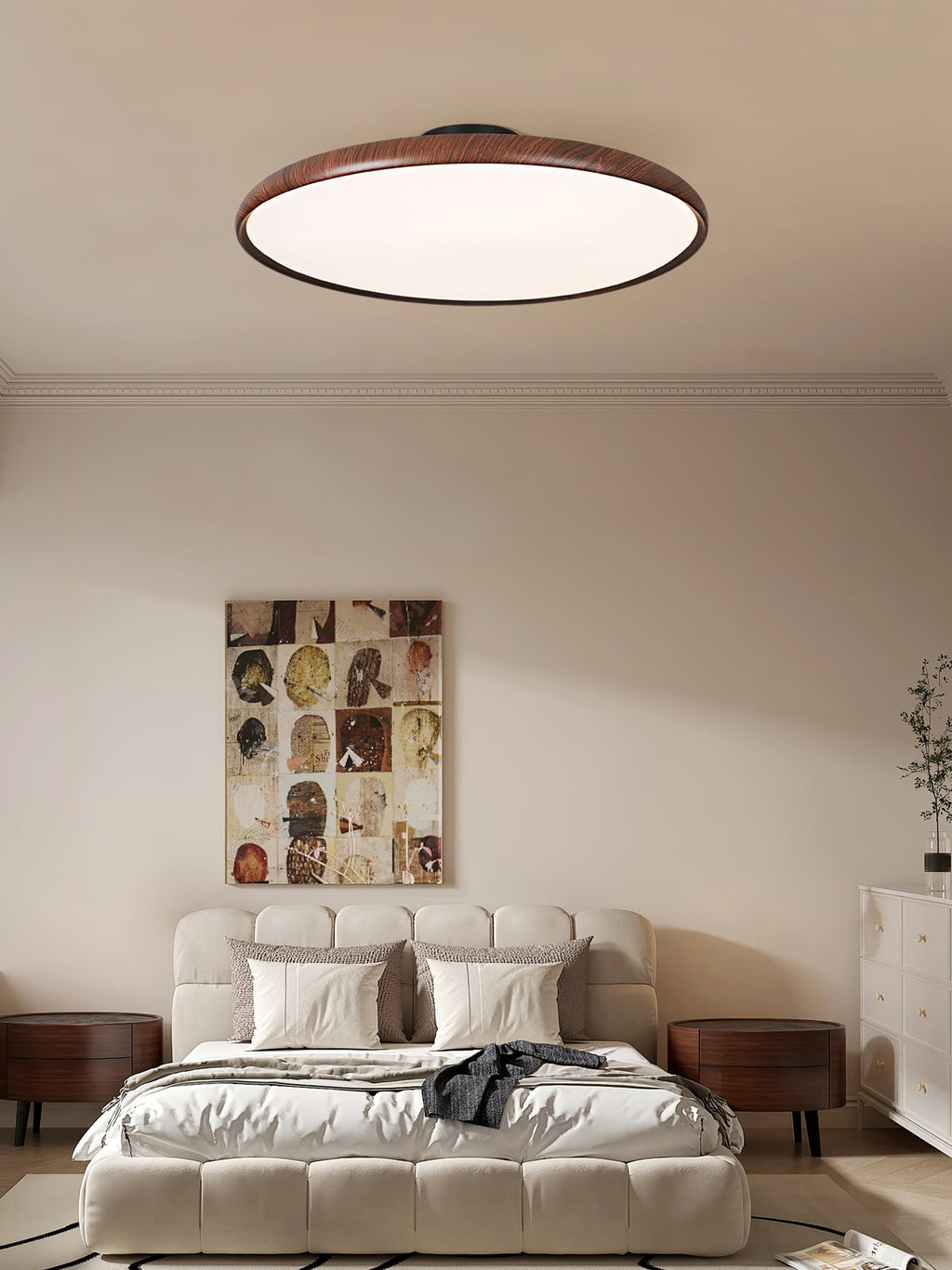 A walnut-grain Clérachic ceiling light above a bed with a tufted cream headboard and a collage artwork, in a calm bedroom.