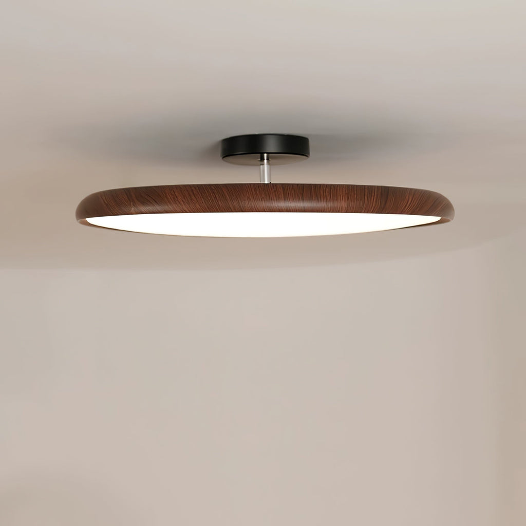Close view of the walnut-grain ring on this Clérachic ceiling light, with its black canopy on a pale ceiling.