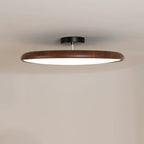 Close view of the walnut-grain ring on this Clérachic ceiling light, with its black canopy on a pale ceiling.