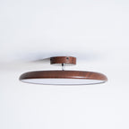 A walnut-grain Clérachic ceiling light with a matching wood-effect canopy and a pale diffuser, against a white ceiling.