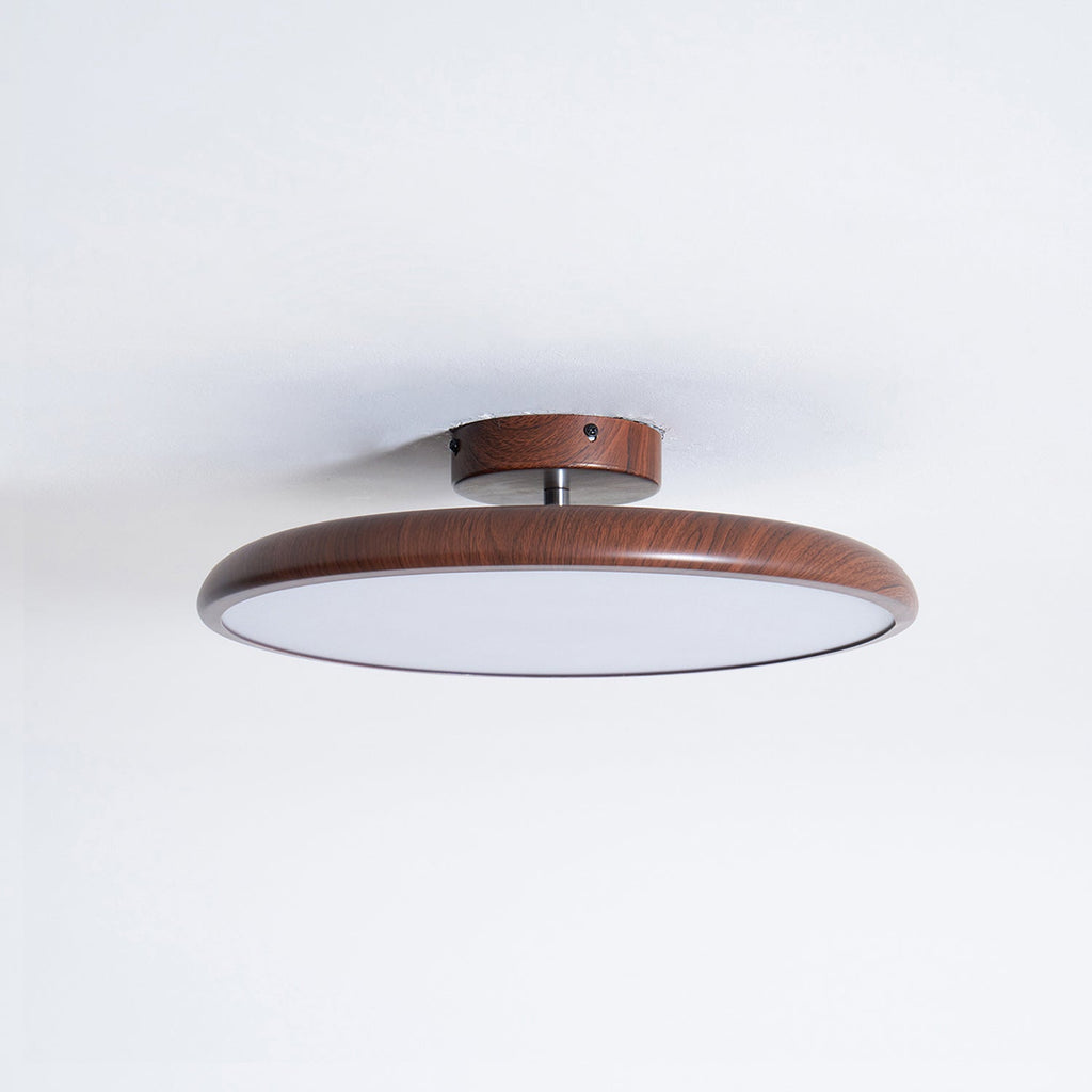 Walnut-grain ring of this Clérachic ceiling light with its unlit diffuser, shown from just below on a white ceiling.