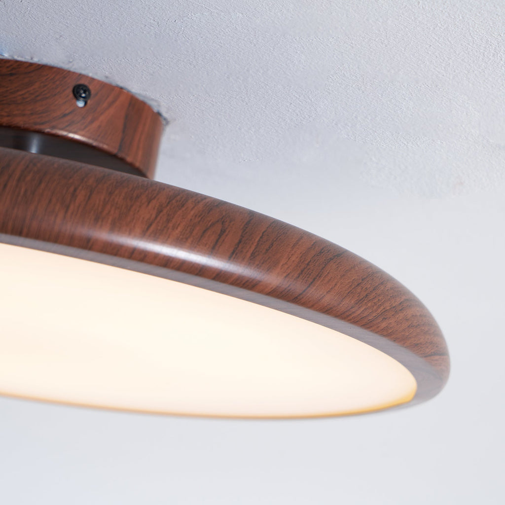 Close view of the walnut wood-grain texture on this Clérachic ceiling light's ring, with its canopy screw and diffuser edge.