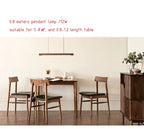 The 80 cm Clérachic walnut beam pendant hanging over a small dining table, sized for tables of 0.8 to 1.2 m.
