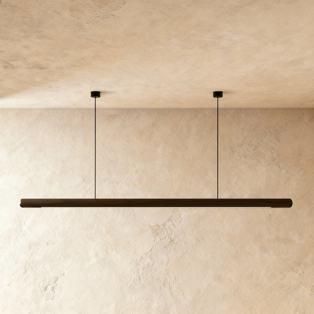 A front view shows the Clérachic black walnut pendant bar lit evenly along its rounded wood profile.