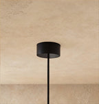 A close view shows the Clérachic pendant's black drum-shaped ceiling canopy and its single thin cable.