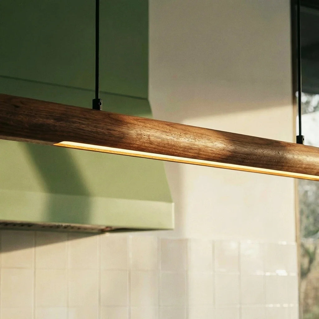 This close view shows the Clérachic black walnut pendant bar's warm glow above a sage green range hood.
