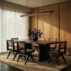 A Clérachic black walnut pendant bar hangs above a dark wood dining table set with woven cane chairs.