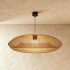Clérachic woven rattan pendant light with an oval lattice shade, hanging from a black cord against a plaster ceiling.