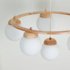 Close view of the wood ring, copper-tone fittings and frosted white globes with wood caps on this Clérachic chandelier.