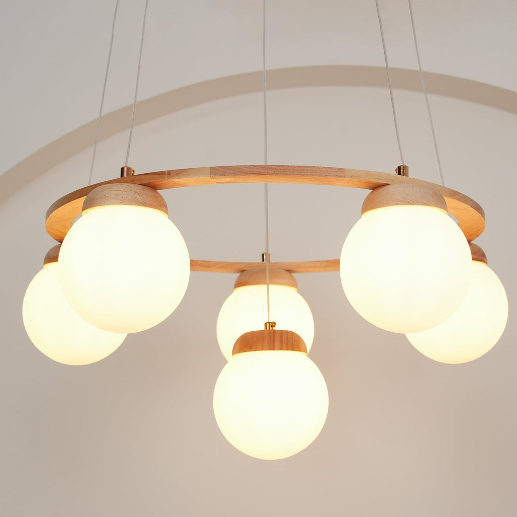 Close and glowing, the frosted globes of this Clérachic chandelier sit under a thin wood ring, with an arch outline on the wall behind.