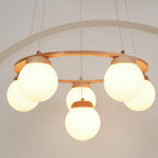 Close and glowing, the frosted globes of this Clérachic chandelier sit under a thin wood ring, with an arch outline on the wall behind.