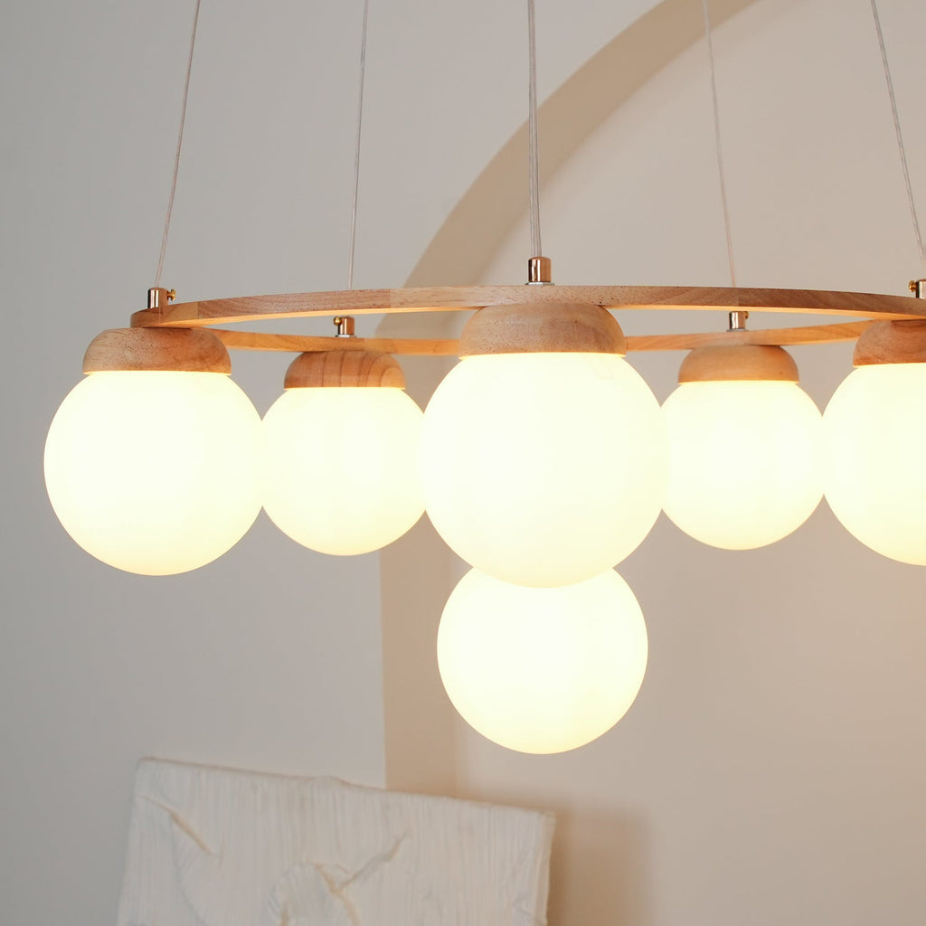 Near view of the glowing frosted globes under the wood ring of this Clérachic chandelier, with the pale arch behind.