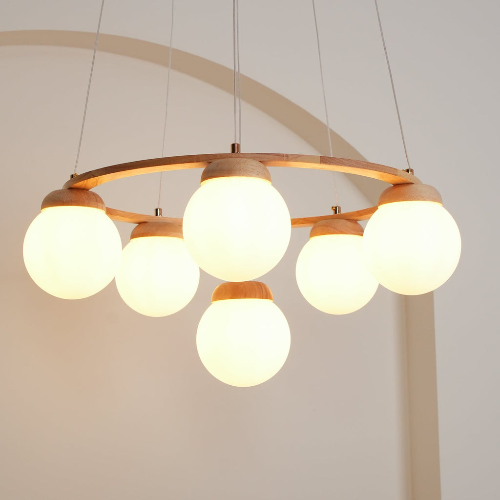 Looking up at the lit globes and wood ring of this Clérachic chandelier, with the arch of the wall curving behind.