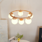 From below, the globes under the light wood ring of this Clérachic chandelier glow warm over a flower vase and books.