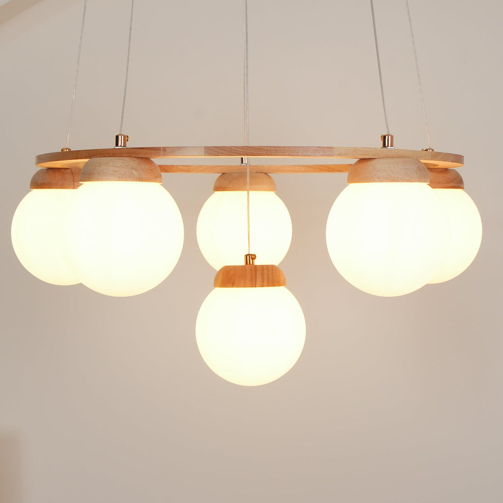 Close view of five large frosted globes lit warm beneath the wood ring on this Clérachic chandelier.