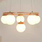 Close view of five large frosted globes lit warm beneath the wood ring on this Clérachic chandelier.
