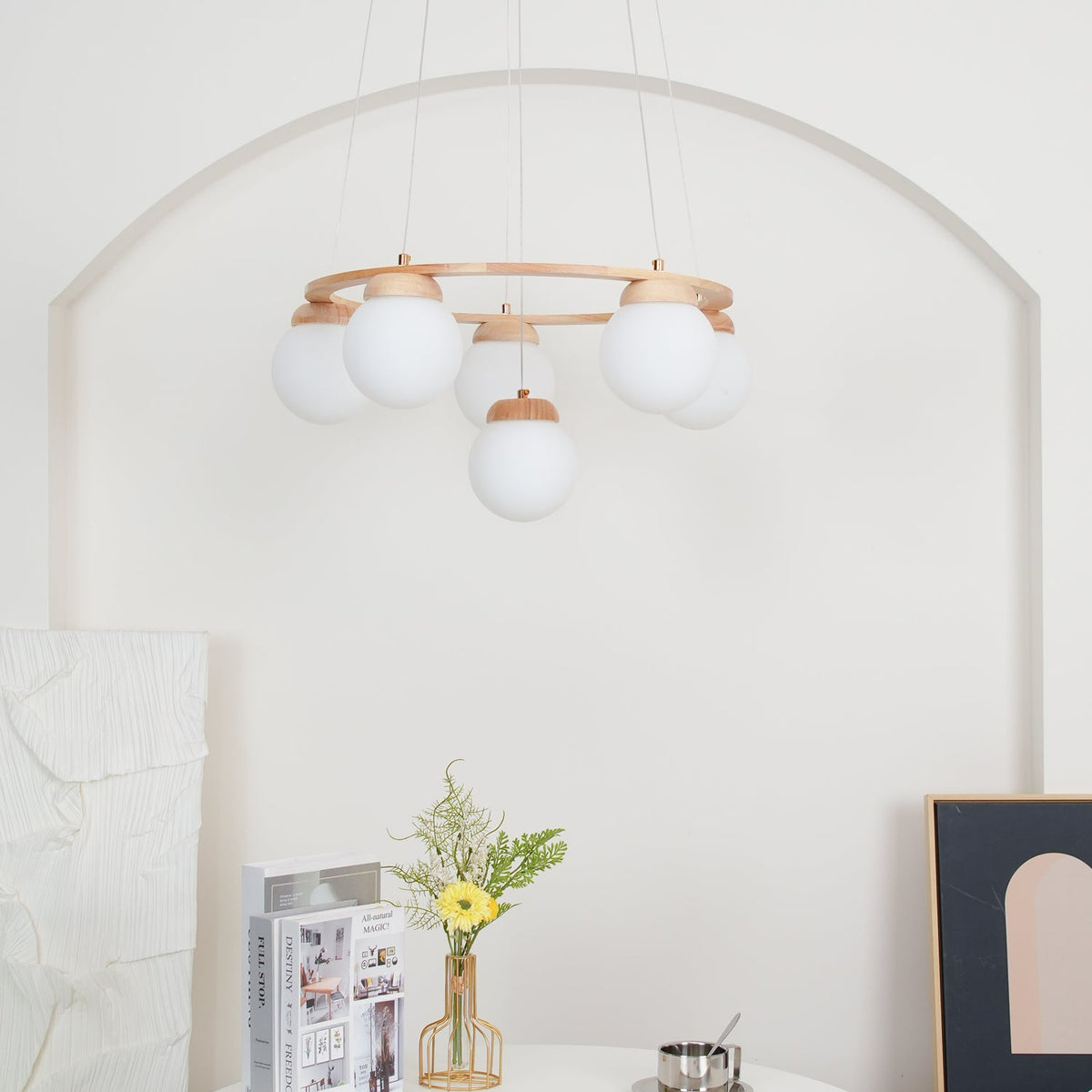 A pale arched wall, flowers and a framed print surround this Clérachic wood-ring chandelier, seen from below with its globes unlit.