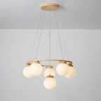 Warm light glows in the cream-tinted globes of this Clérachic chandelier, hung from a wood plate against a pale grey wall.