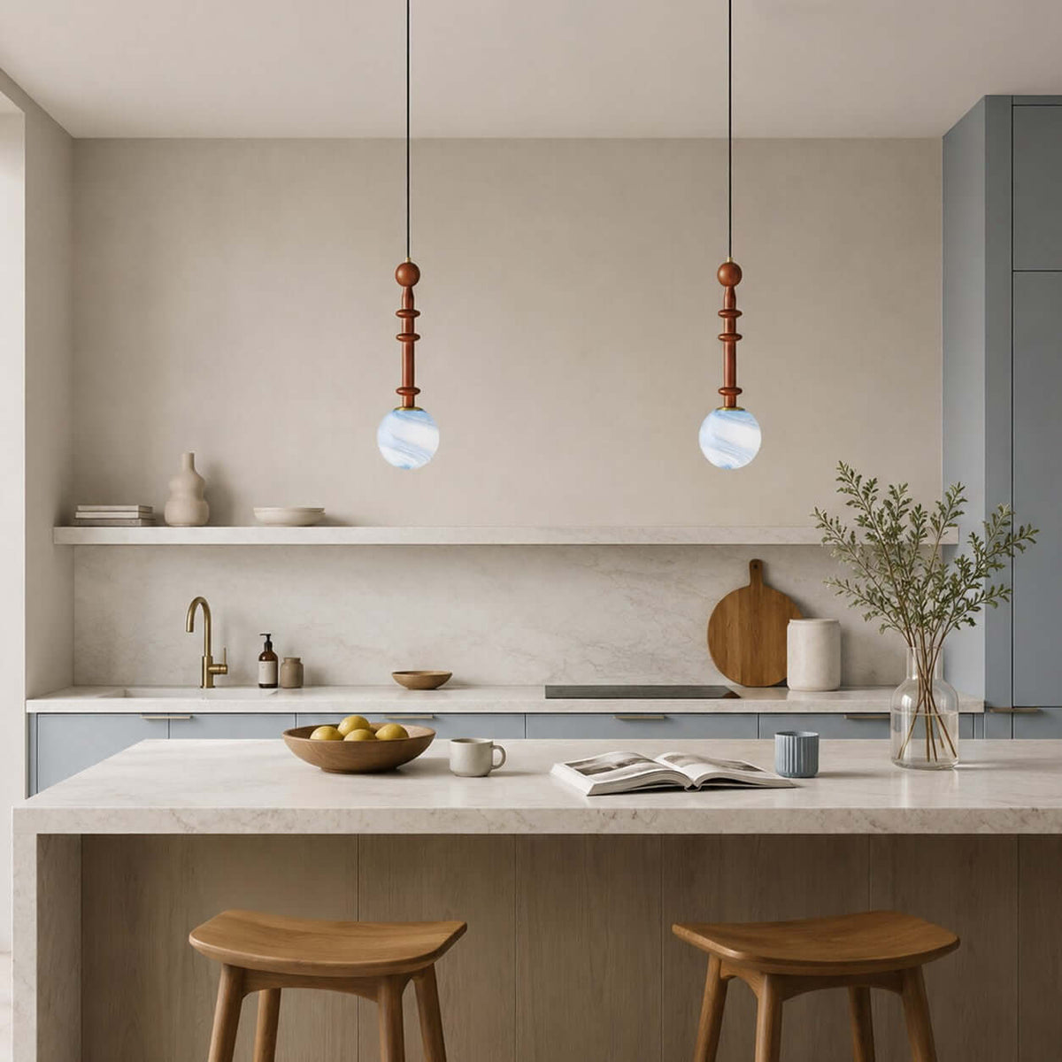 A pair of Clérachic pendants with blue-white globes hangs above a stone kitchen island with two wooden stools.
