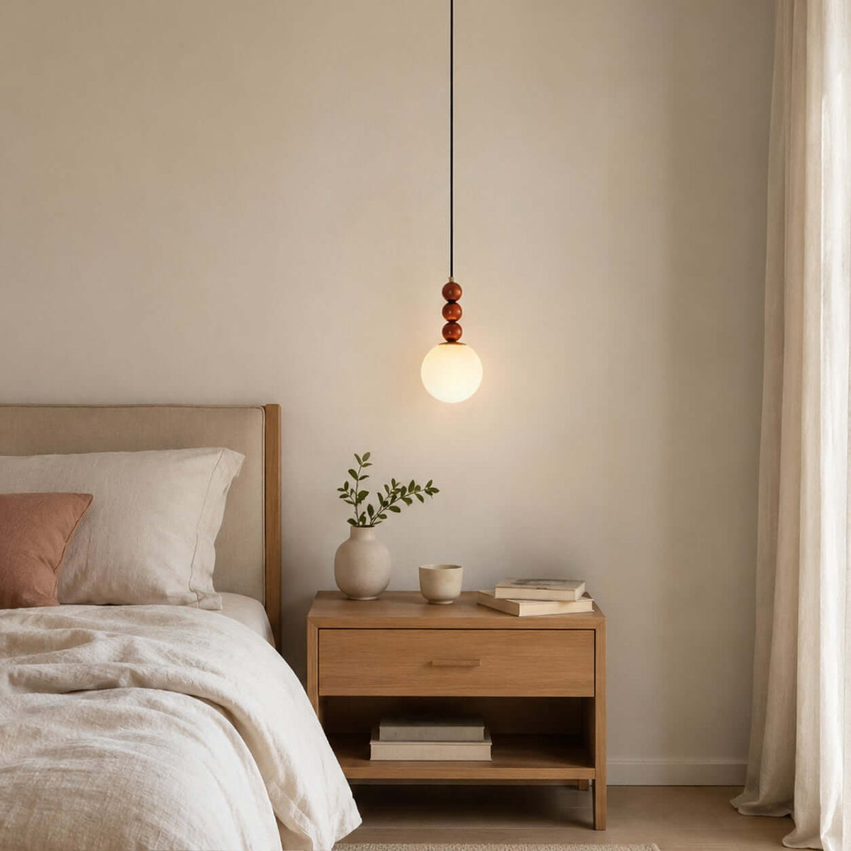 Beside a linen-dressed bed, this Clérachic pendant glows with a warm white globe above a wooden bedside table.