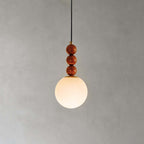 A frosted white glass globe below three round wooden beads on this Clérachic pendant, lit on a soft grey backdrop.