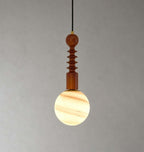 The ribbed wood stem and a cream-and-amber banded globe of this Clérachic pendant, lit against a plain grey wall.