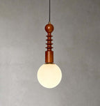 A frosted white globe glows beneath the ribbed wooden stem of this Clérachic pendant, against a textured grey wall.