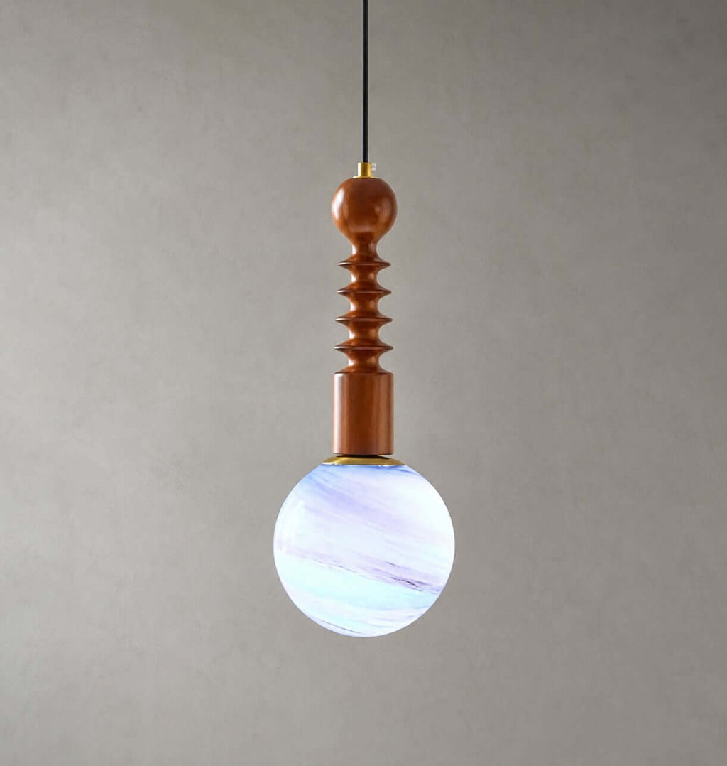 Blue and violet swirls through the glass globe of this Clérachic pendant, which has a ribbed wooden stem, on grey.
