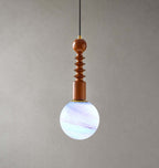 Blue and violet swirls through the glass globe of this Clérachic pendant, which has a ribbed wooden stem, on grey.