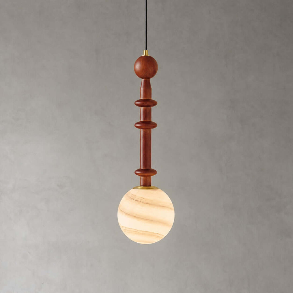 The slender wood stem of this Clérachic pendant sits above a globe banded in cream and caramel, on a grey wall.
