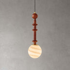 The slender wood stem of this Clérachic pendant sits above a globe banded in cream and caramel, on a grey wall.