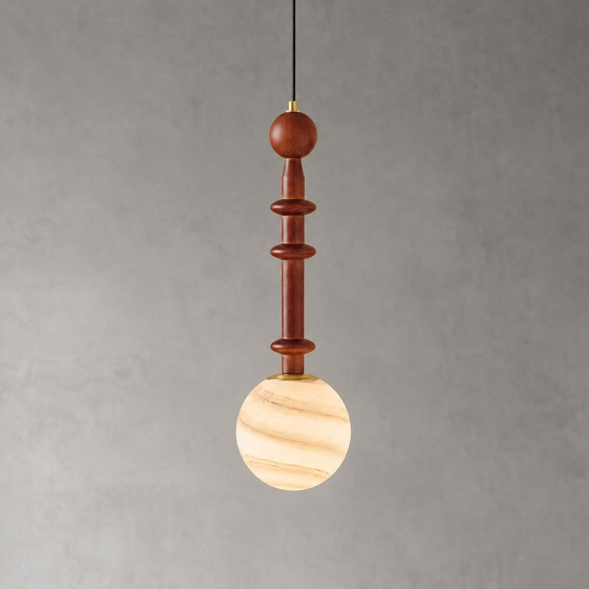The slender wood stem of this Clérachic pendant sits above a globe banded in cream and caramel, on a grey wall.