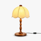 Clérachic table lamp with a scalloped cream shade and a turned walnut stem and base, with an inline switch on the cord, on white.