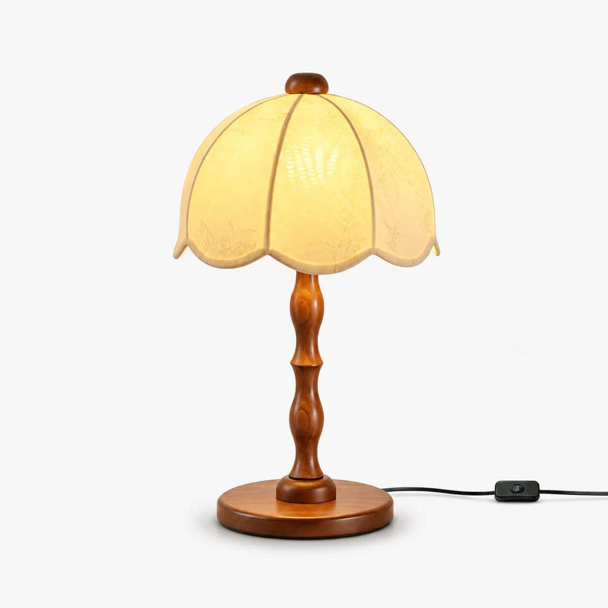 Clérachic table lamp with a scalloped cream shade and a turned walnut stem and base, with an inline switch on the cord, on white.
