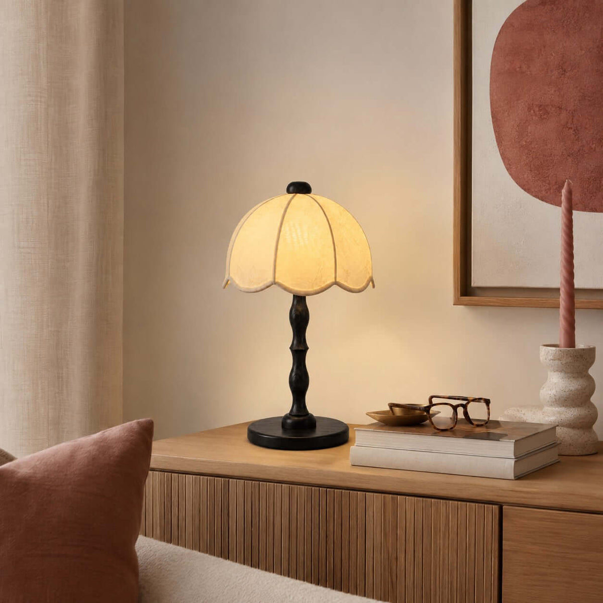 Clérachic table lamp with a black base and scalloped shade on a ribbed wooden cabinet, with glasses and a book stack beside it.