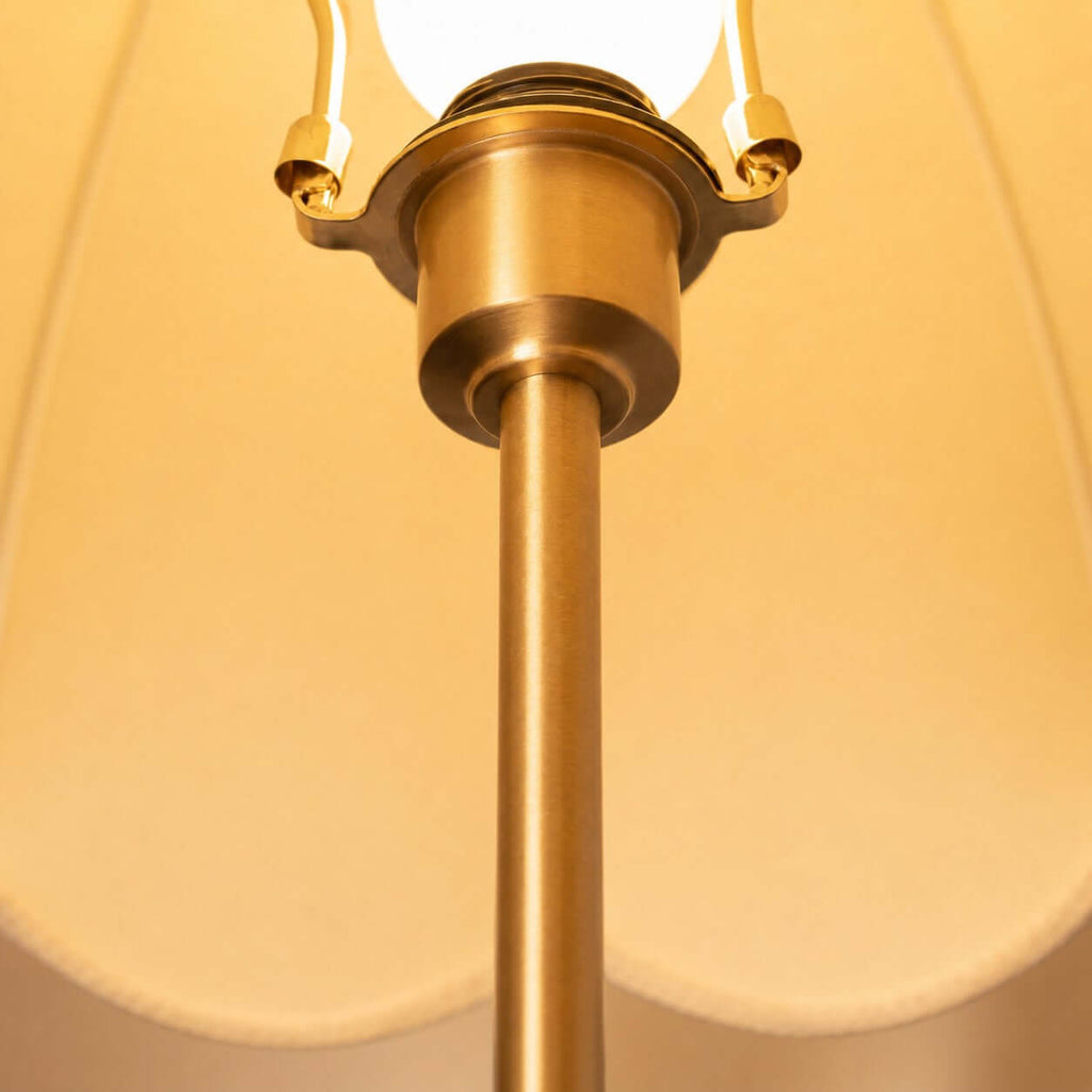 Close view of the brass socket and stem under the lit scalloped shade of this Clérachic table lamp.
