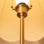 Close view of the brass socket and stem under the lit scalloped shade of this Clérachic table lamp.