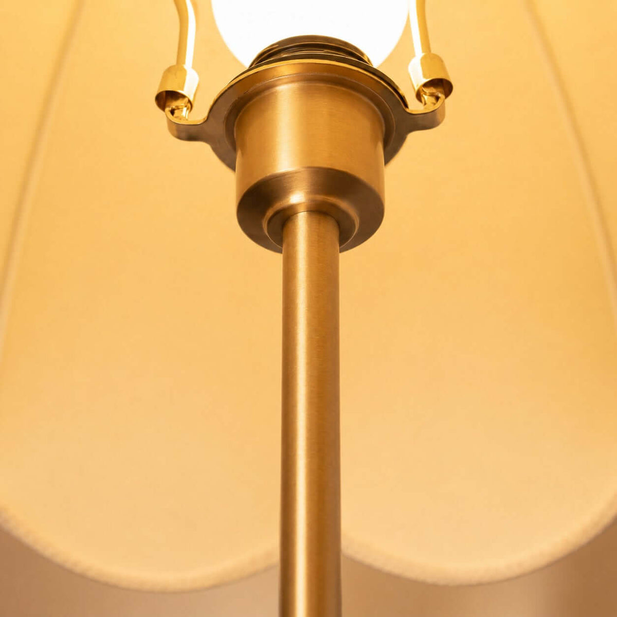 Close view of the brass socket and stem under the lit scalloped shade of this Clérachic table lamp.