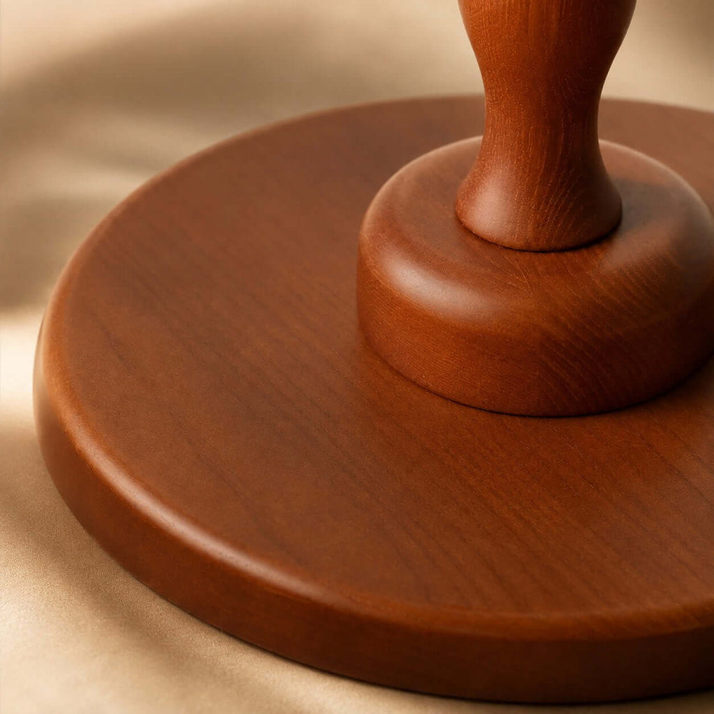 Close view of the smooth, rounded walnut base and the foot of the turned stem on this Clérachic table lamp.