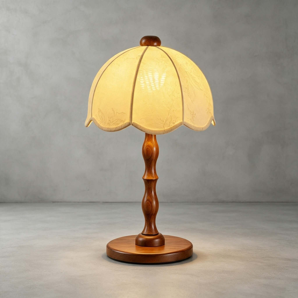 A Clérachic table lamp with a walnut turned stem and round base, lit on a concrete-grey studio backdrop.