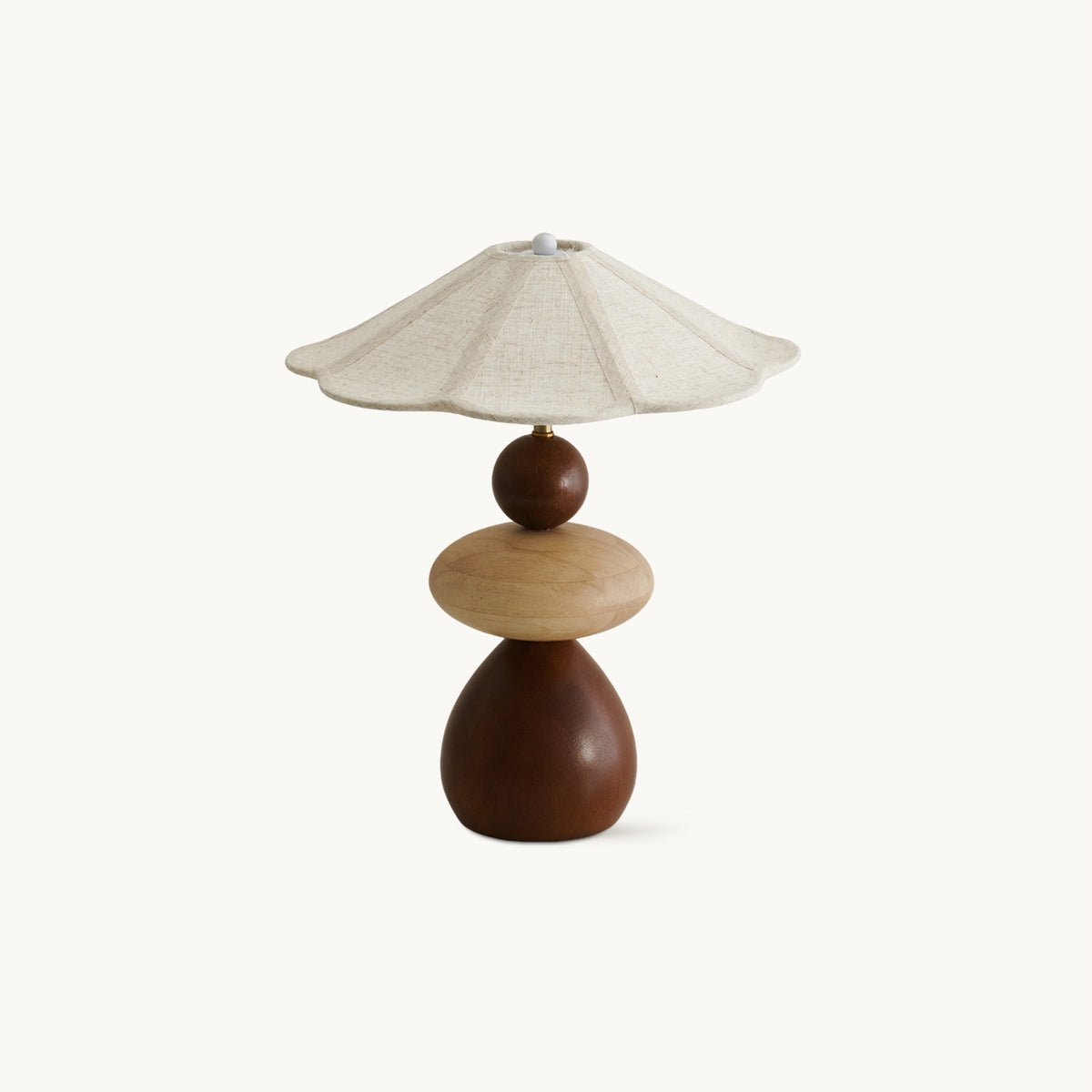 A Clérachic table lamp on a plain white backdrop, with a scalloped linen shade over stacked walnut and pale wood shapes.