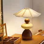 Seen from the side, this Clérachic table lamp stands on a wooden table beside an open wooden tray box and a small picture frame.