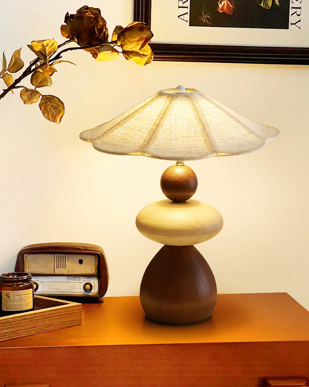 A Clérachic table lamp on an orange-toned wooden shelf, with a vintage radio, a small tray and a dried branch behind it.
