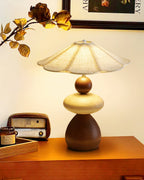 A Clérachic table lamp on an orange-toned wooden shelf, with a vintage radio, a small tray and a dried branch behind it.