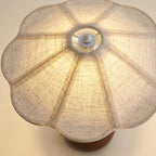 Looking at the underside of the scalloped linen shade on this Clérachic table lamp, with its ribbed seams and the lit bulb area.